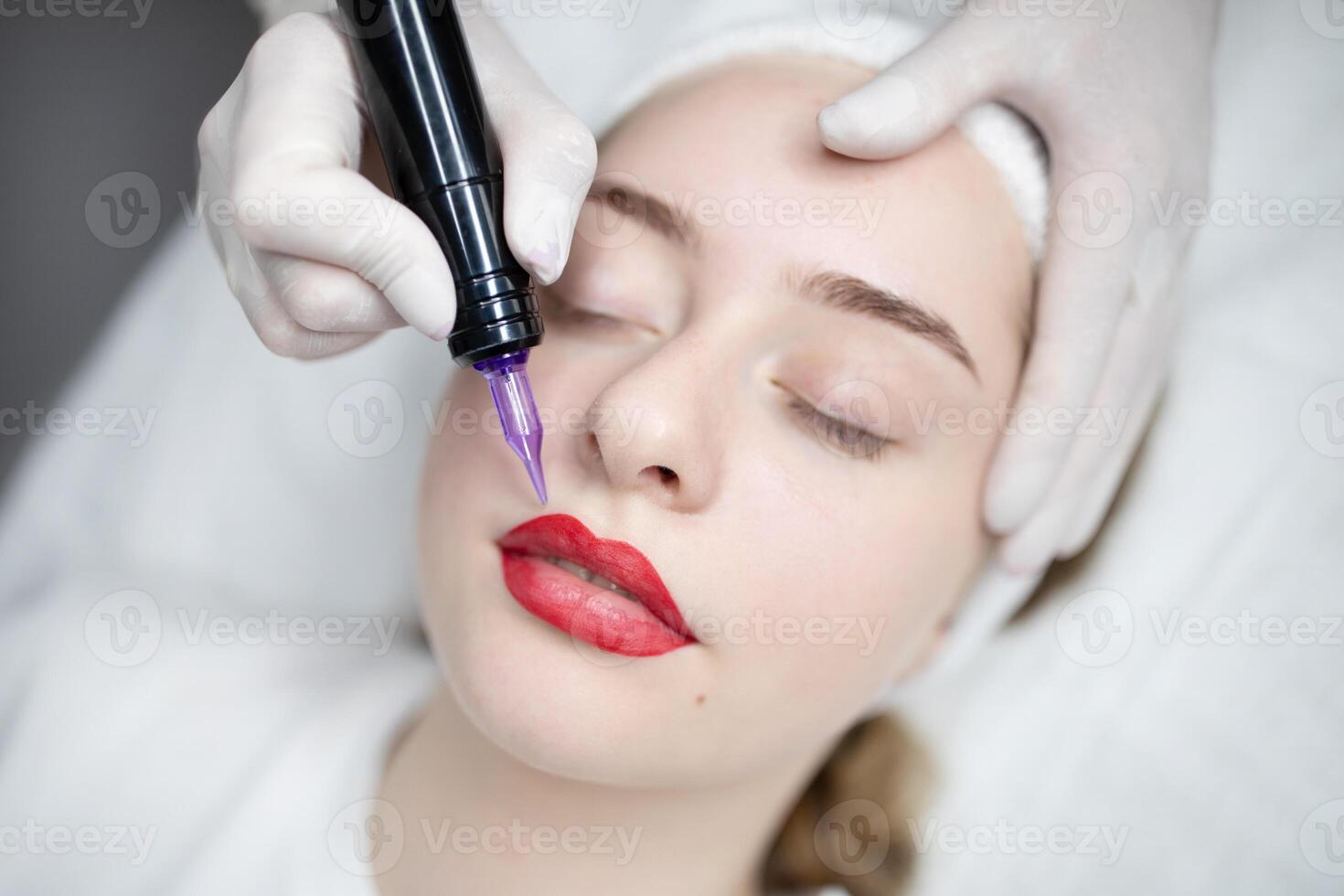 A woman receives a permanent makeup procedure at a beauty salon. The session focuses on enhancing her lips with a rich color, ensuring a fresh look that requires minimal maintenance. photo