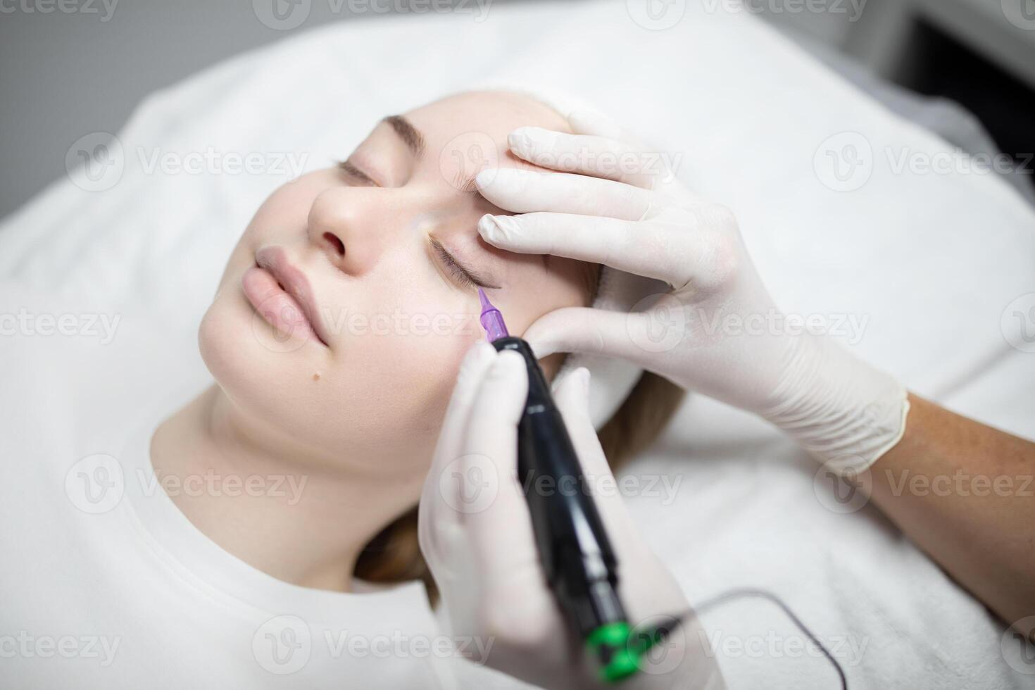 A beautician applies permanent makeup on a woman's eyebrows during a pampering session at a beauty salon. The process aims to enhance features with long-lasting results. photo