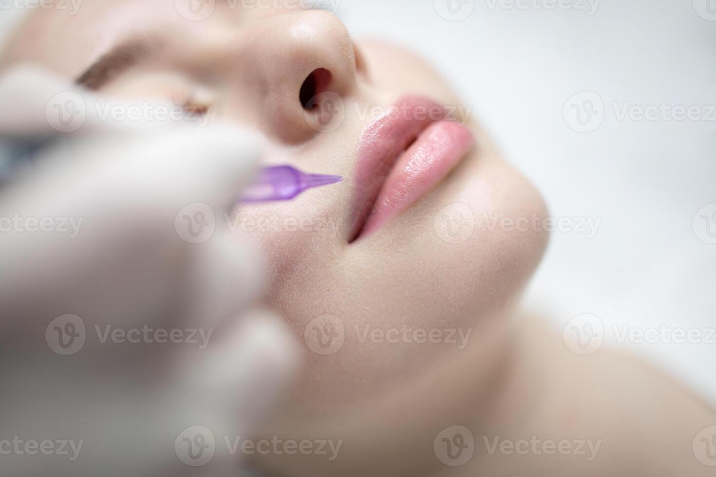 In a tranquil beauty salon, a woman relaxes as a skilled artist applies permanent makeup to enhance her lips. The pampering session focuses on achieving a natural, long-lasting look. photo
