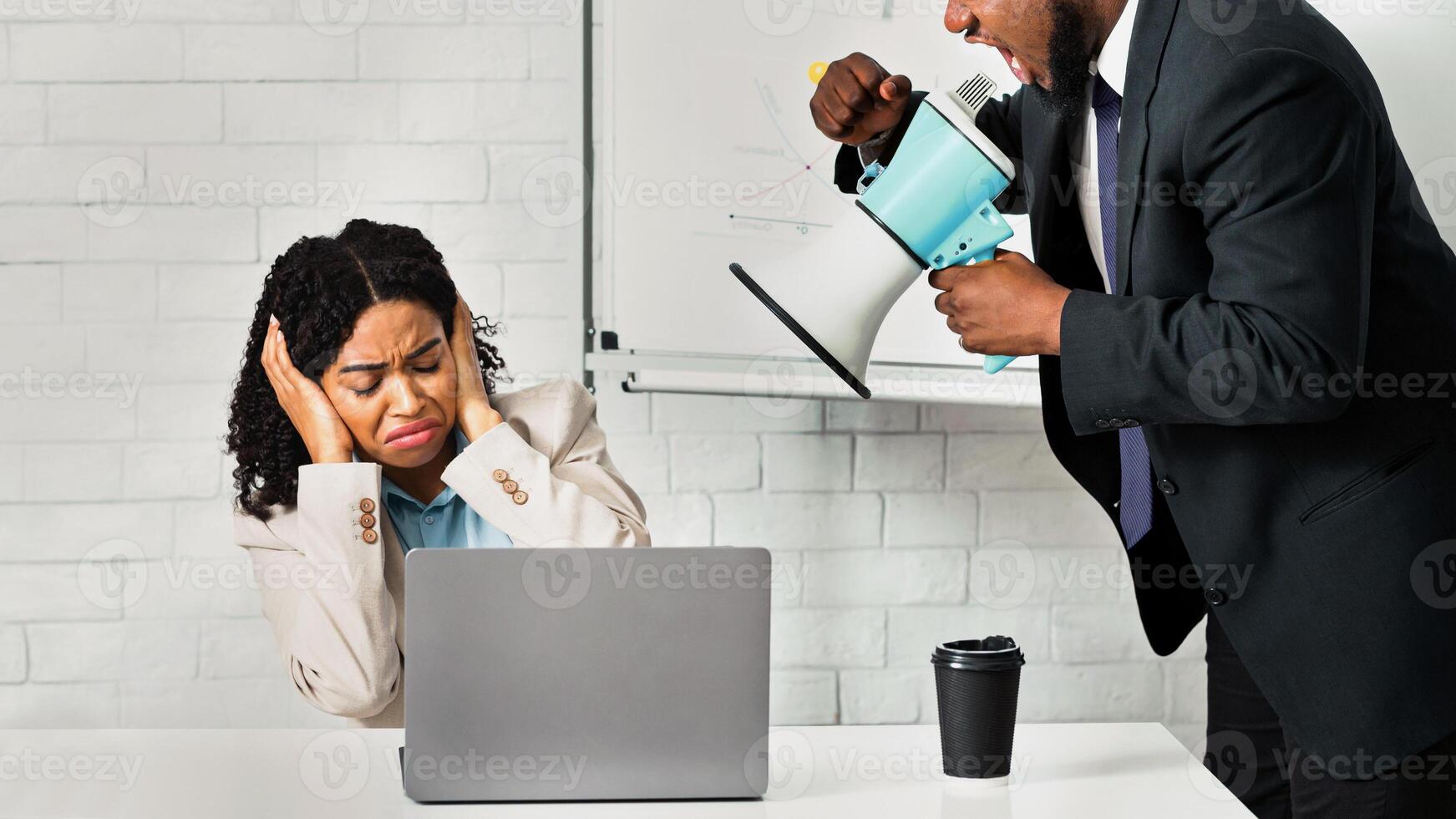 Angry boss with megaphone shouting at employee in office photo