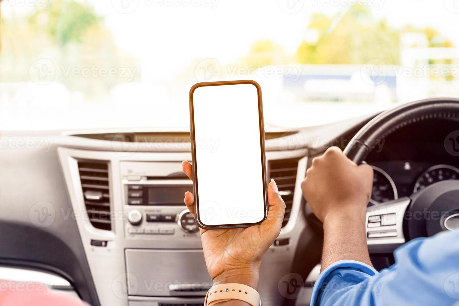 Back rear over the shoulder view of happy black female passenger holding smartphone with white blank screen, mock up, sitting on front seat in car. Couple using mobile app for navigation, copy space photo