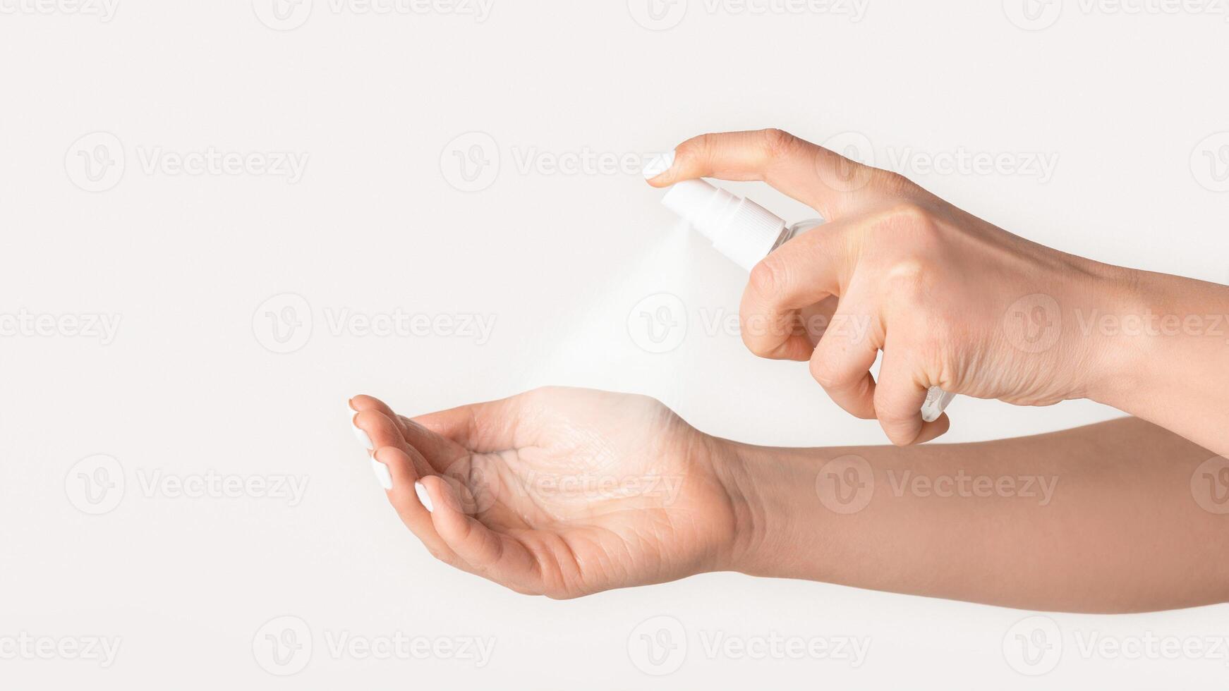 Antiviral hygiene measures. Closeup of female hands applying antiseptic on light background photo