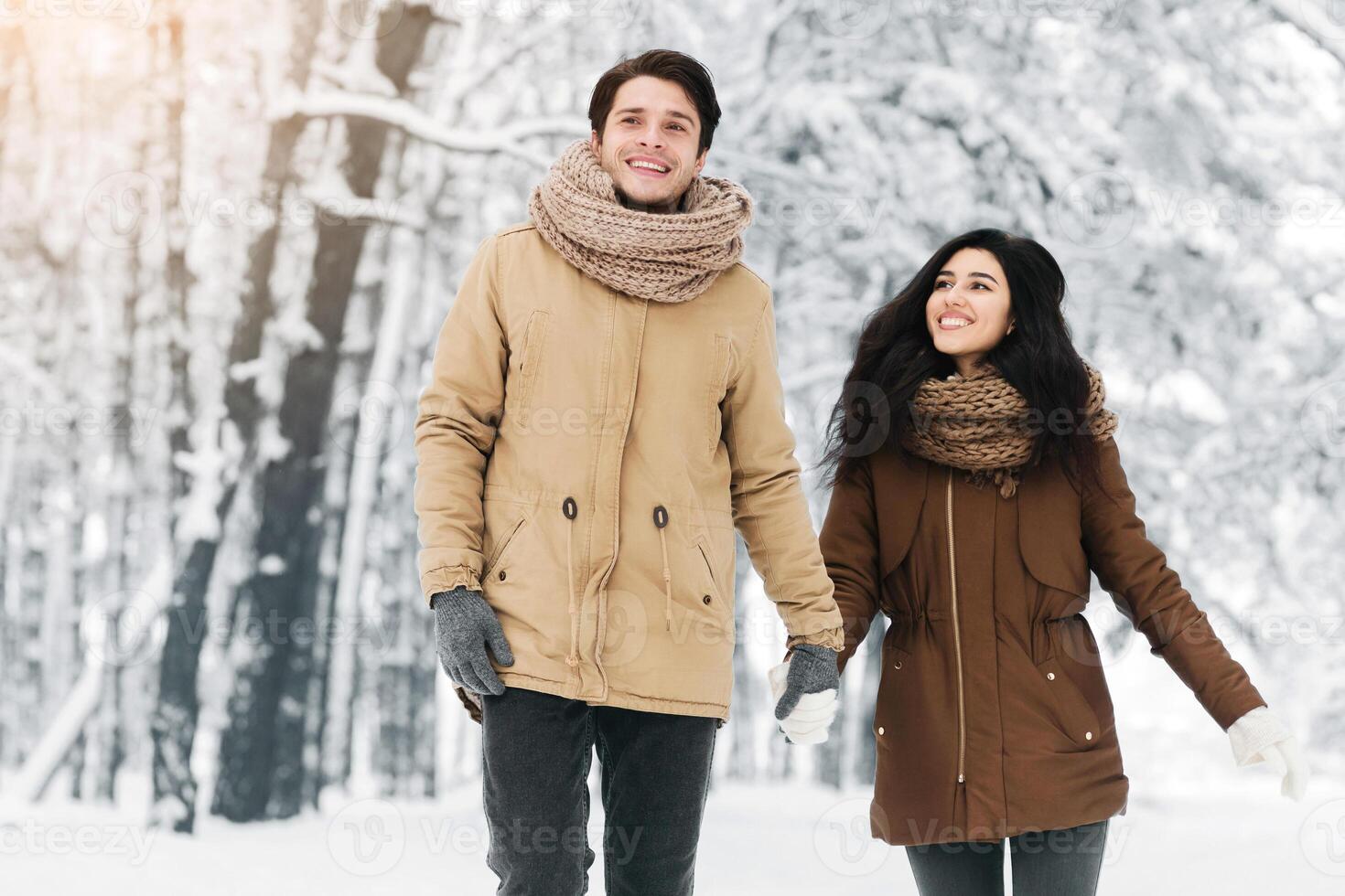 Winter Concept. Smiling Couple Of Lovers Walking Holding Hands In Snowy Forest On Christmas Morning Outdoors photo