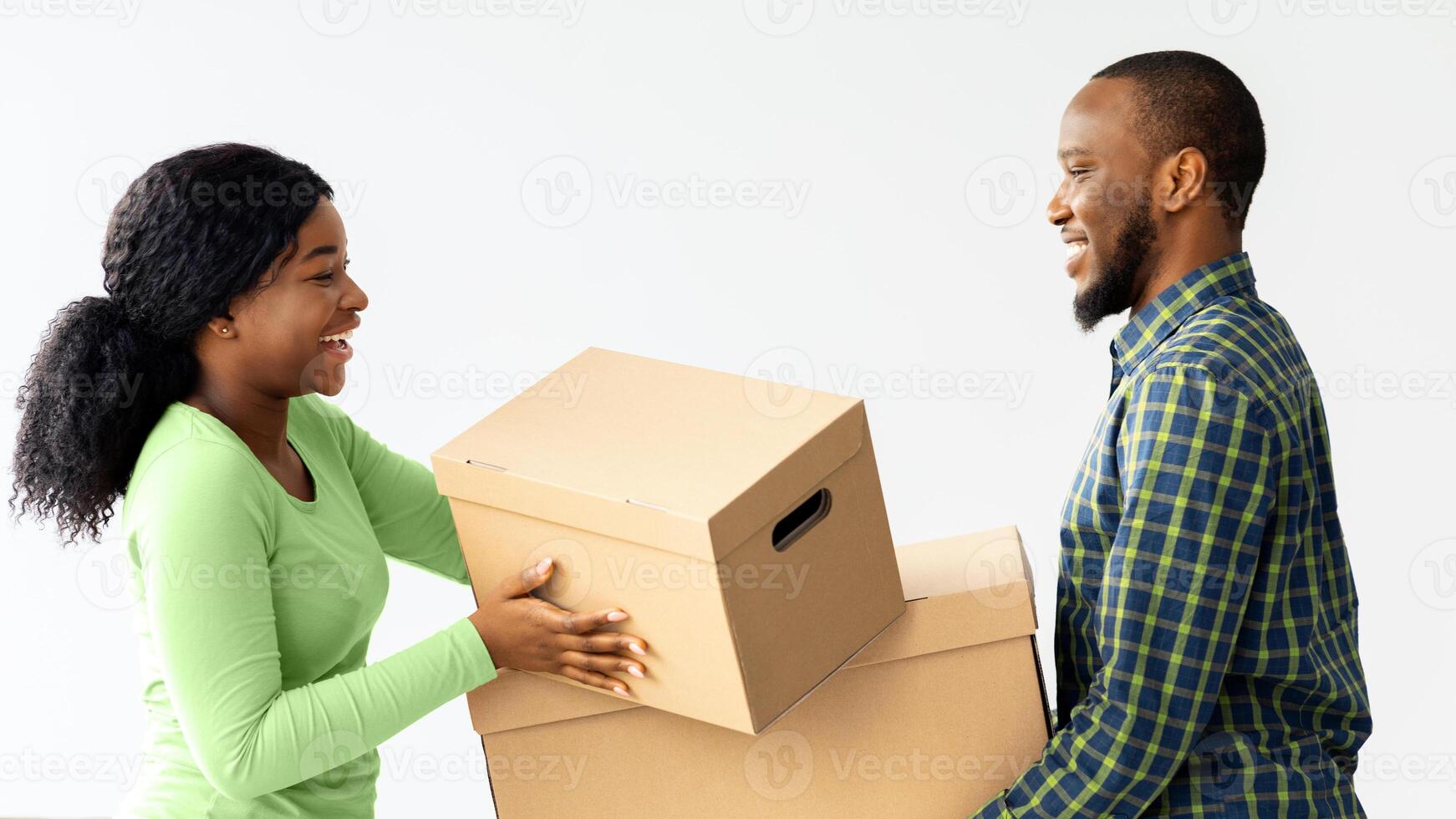 Happy Young Black Spouses Moving To New Apartment, Carrying Belongings In Cardboard Boxes And Smiling To Each Other, African American Couple Enjoying Relocation To Their Own Flat, Free Space photo