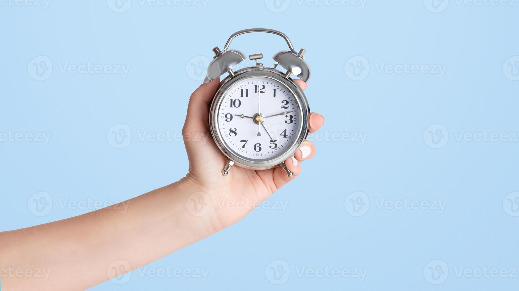 Girl hand showing alarm clock on white background, close up with copy space. Panorama photo