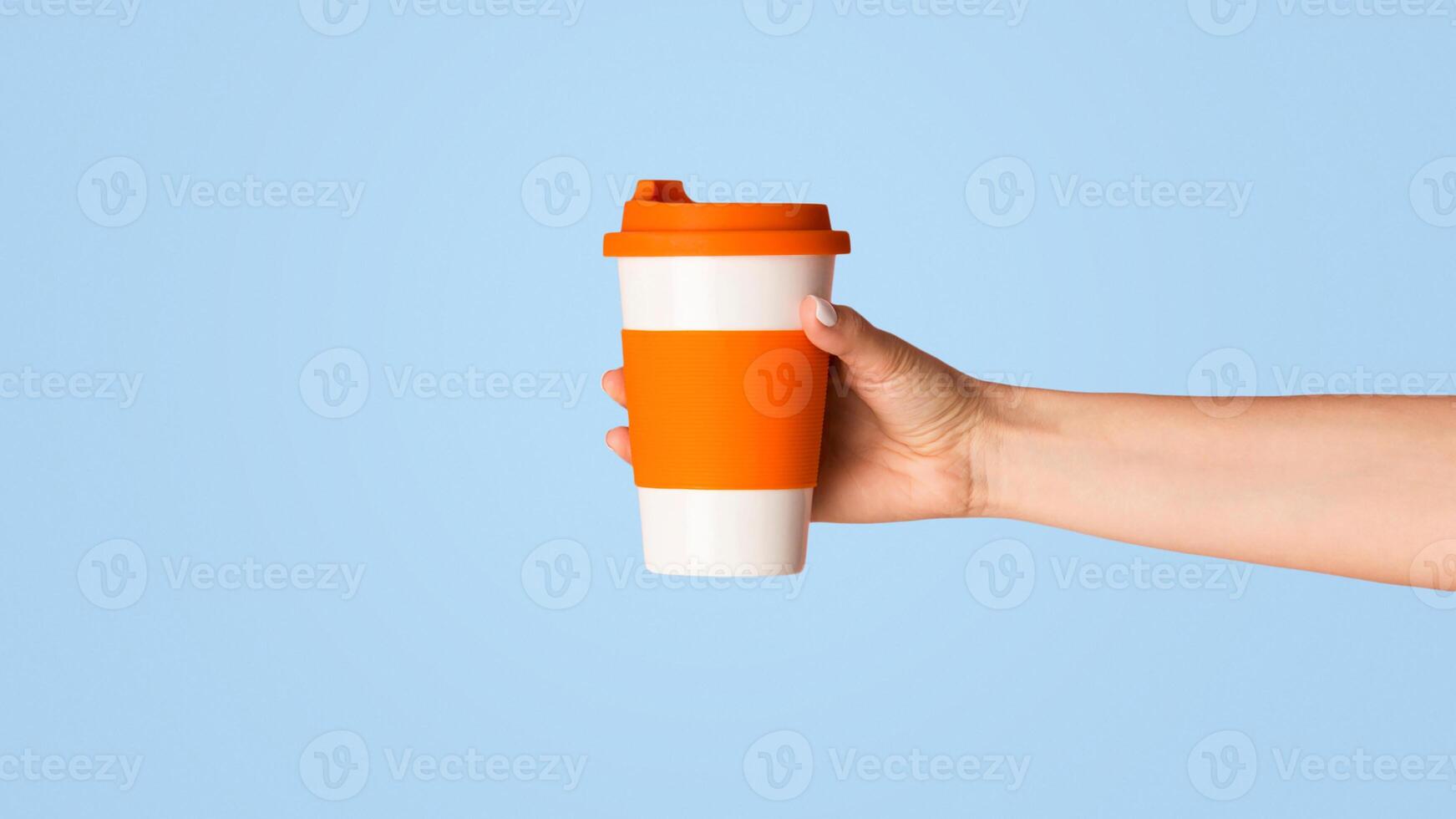 Millennial girl holding reusable eco cup with hot beverage on pink background, close up view photo