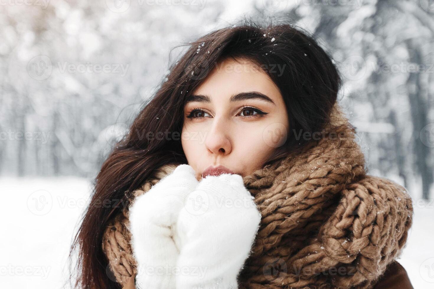 Cold Winter. Dreamy Girl Blowing On Hands In Gloves Trying To Warm Up Standing In Snowy Forest photo