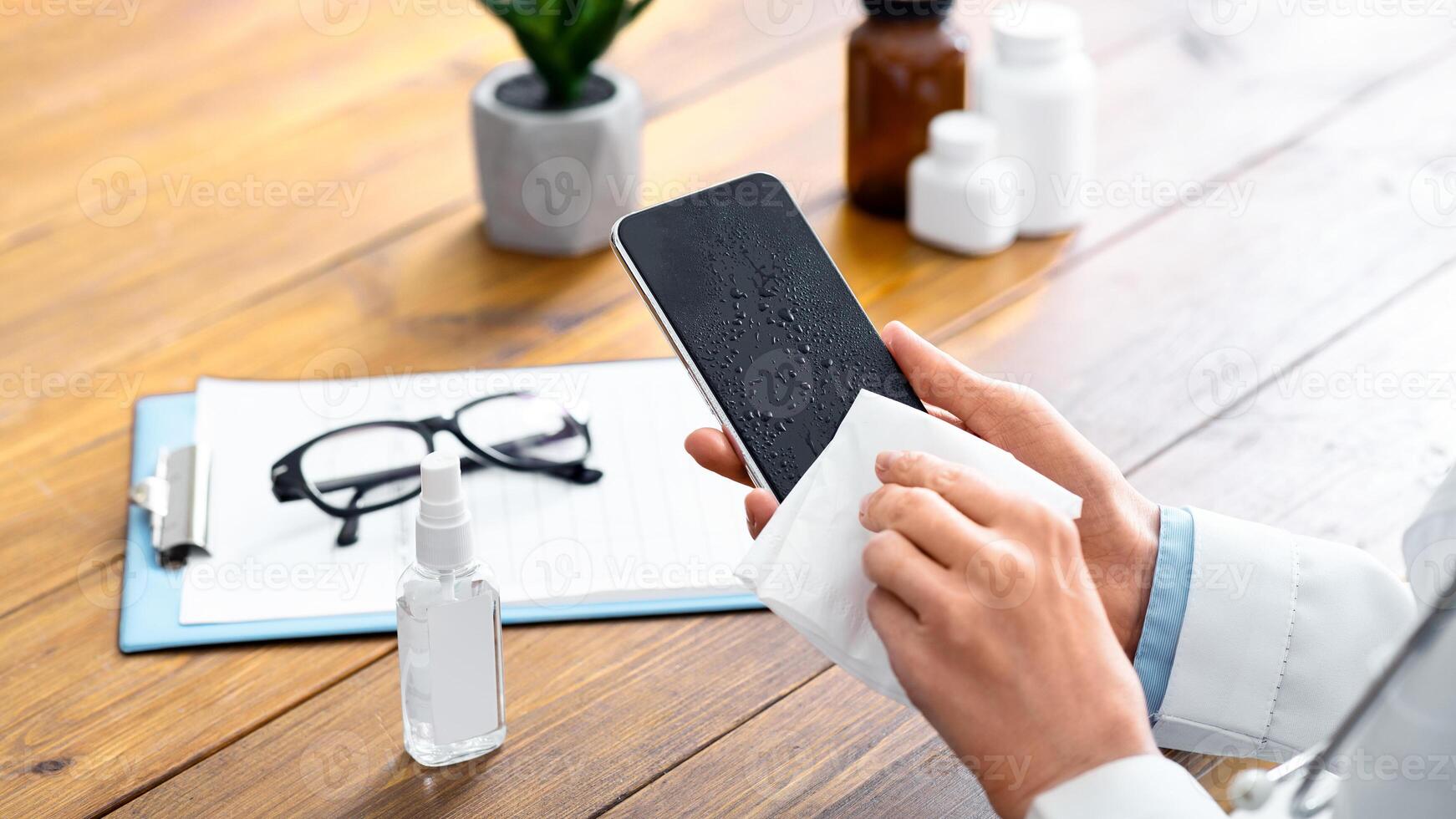 Smartphone disinfection. Female doctor using sanitizer and wipes, cleans phone in office photo