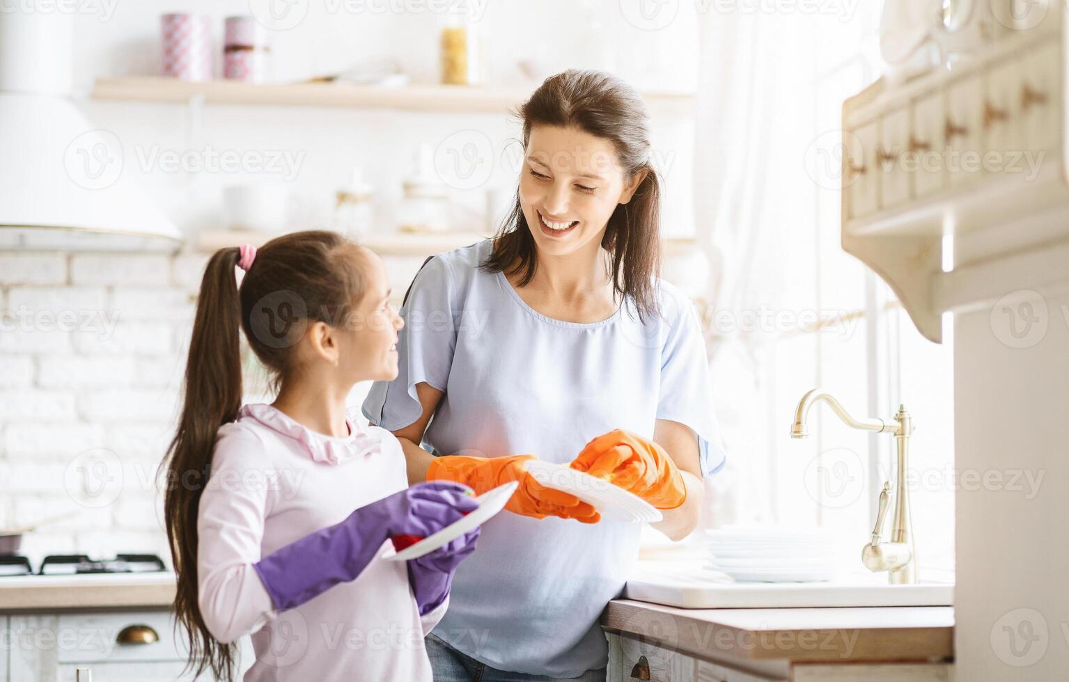 Helping hand. Cute Teenage Girl Help Her Mother In Washing Dishes At Family Kitchen photo