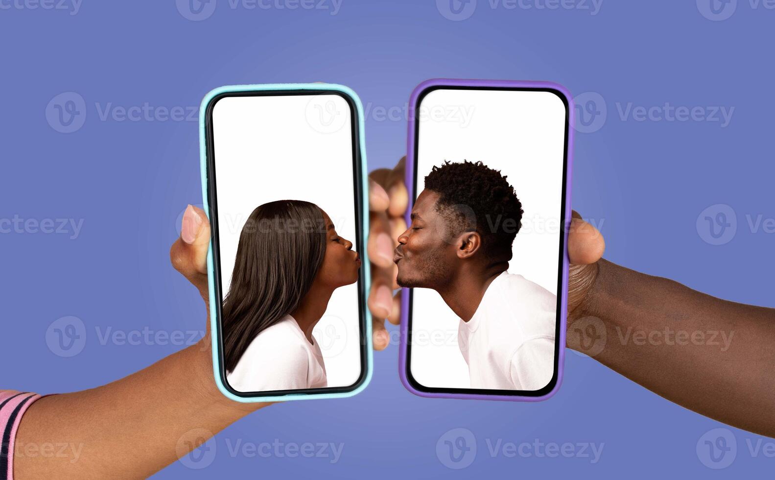 A couple is seen sharing a romantic kiss, each holding a smartphone displaying the other face. This intimate moment captures the bond of love and connection through technology. photo