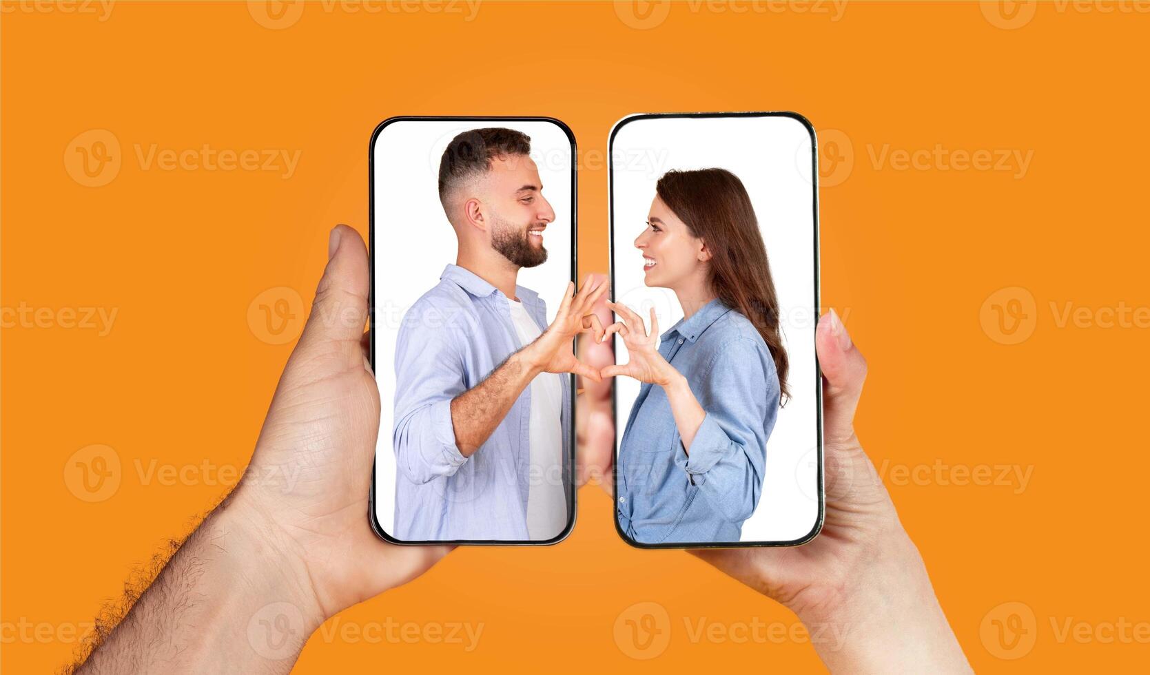 A couple interacts through their smartphones, forming heart shapes with their hands while engaged in a texting conversation. This moment emphasizes their connection despite distance. photo
