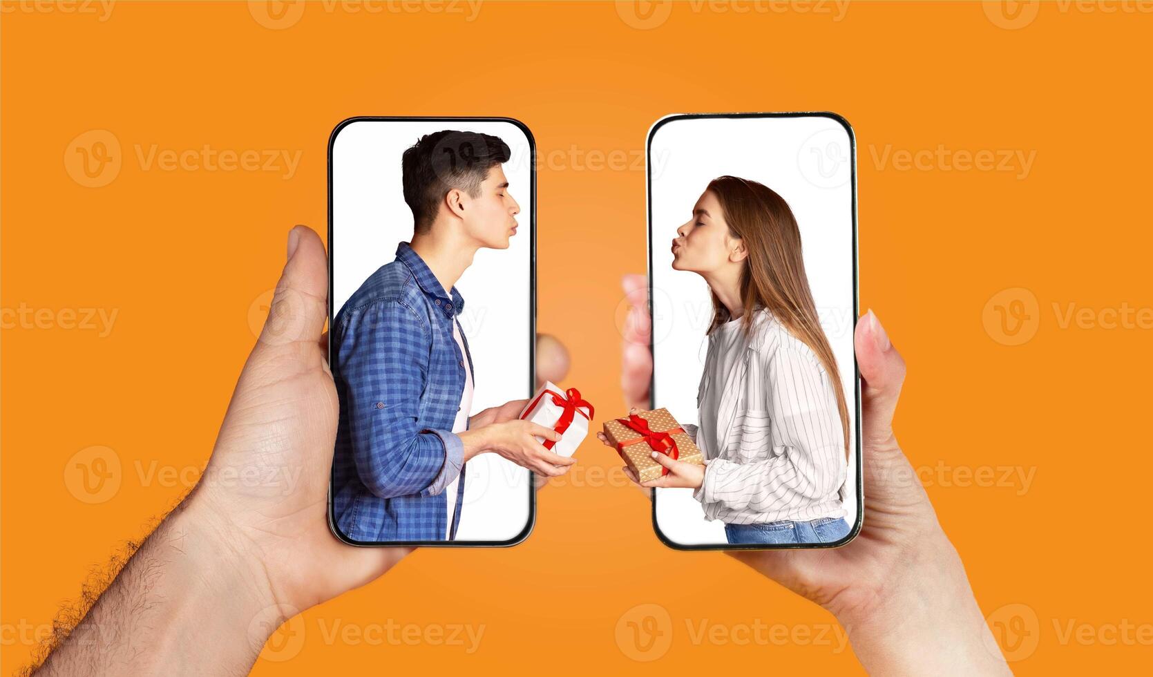 A young couple expresses their affection through a virtual exchange on their smartphones. Each holds a gift while sharing playful kisses, showcasing modern romance and connection. photo