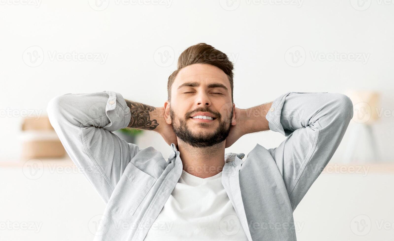 Taking break. Happy freelancer guy leaning back in chair, relaxing after successful work, working on laptop computer in home office, resting at workplace with hands behind head photo