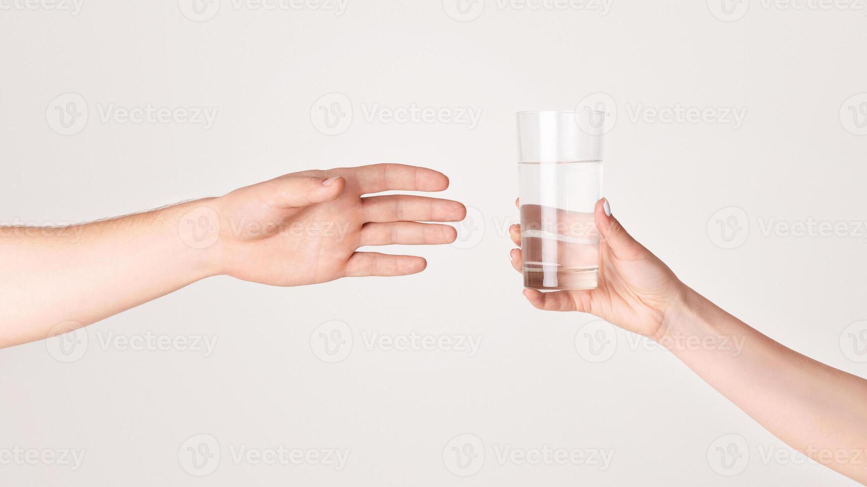 Young girl giving glass of fresh clear water to man on light background, close up of hands. Panorama photo