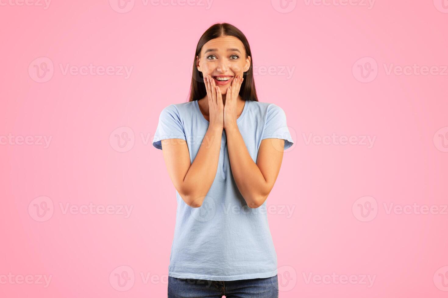 Wow, Omg. Impressed Smiling Young Lady Touching Face, Expressing Positive Emotion. Amazed Young Woman Looking At Camera Posing Over Yellow Studio Background. Appreciation Concept photo