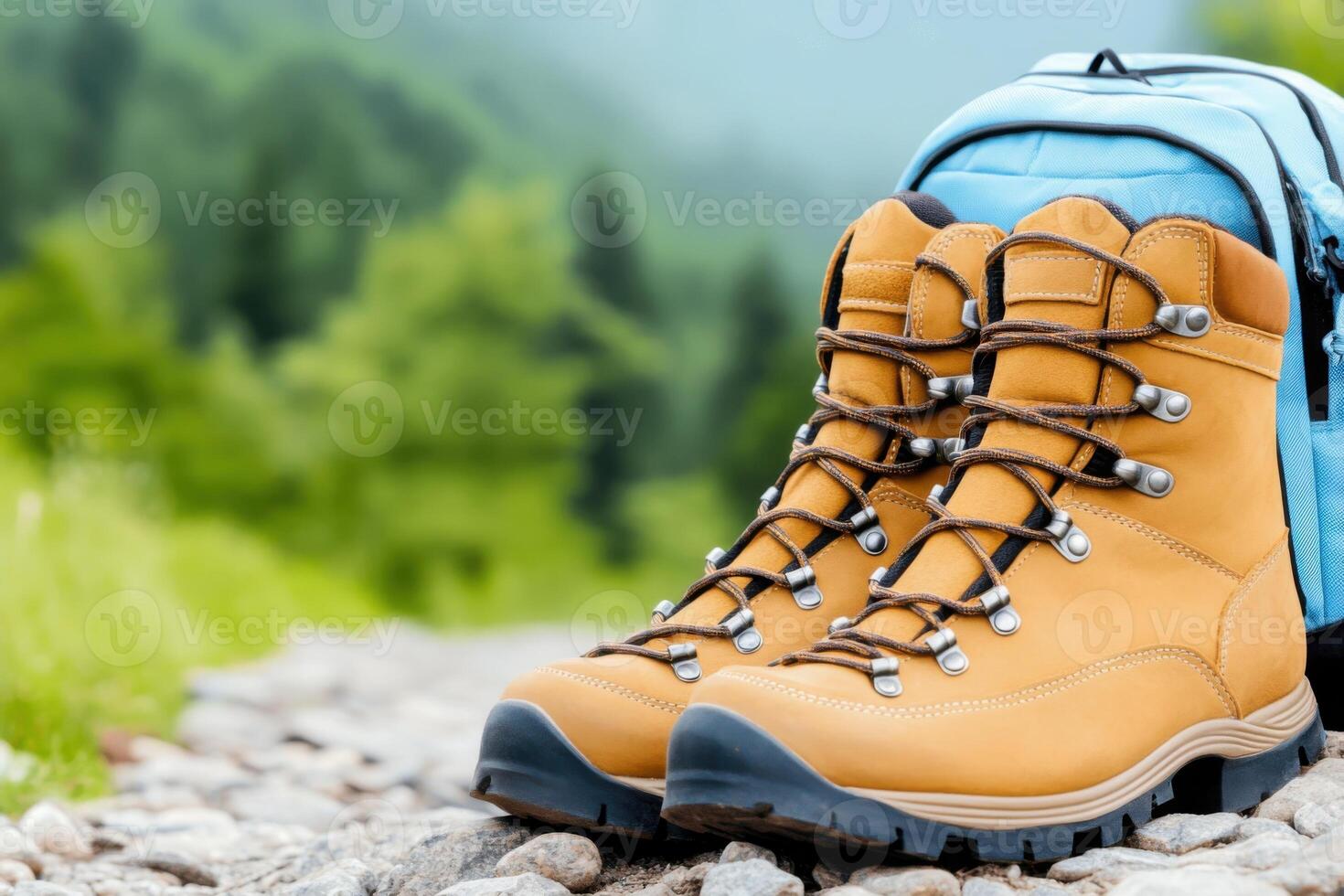 Brown hiking boots resting on rocky path with blue backpack nearby in a lush green landscape photo