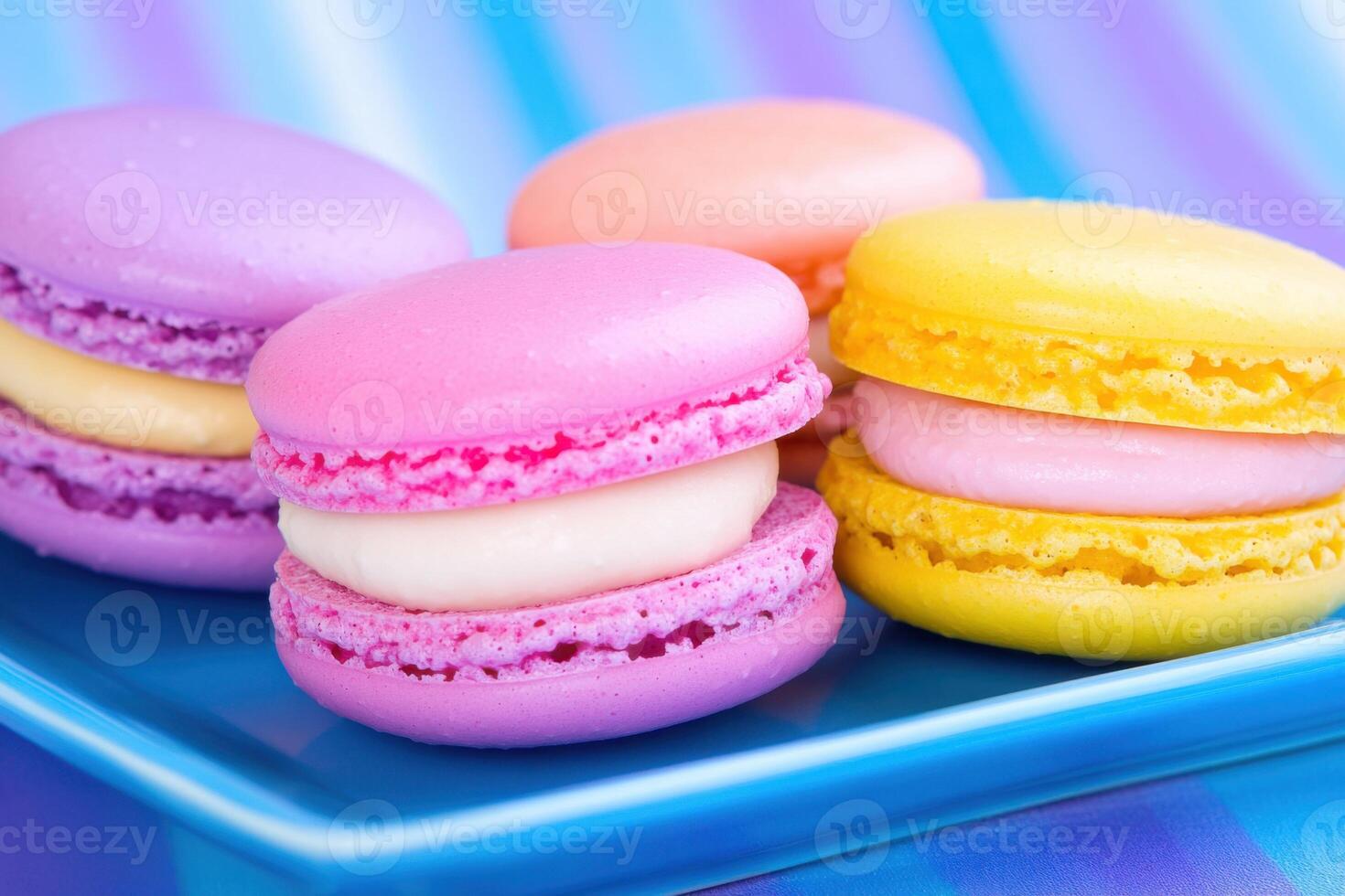Colorful macarons in vibrant hues styled on a blue plate showcasing dynamic lighting and delightful dessert presentation photo