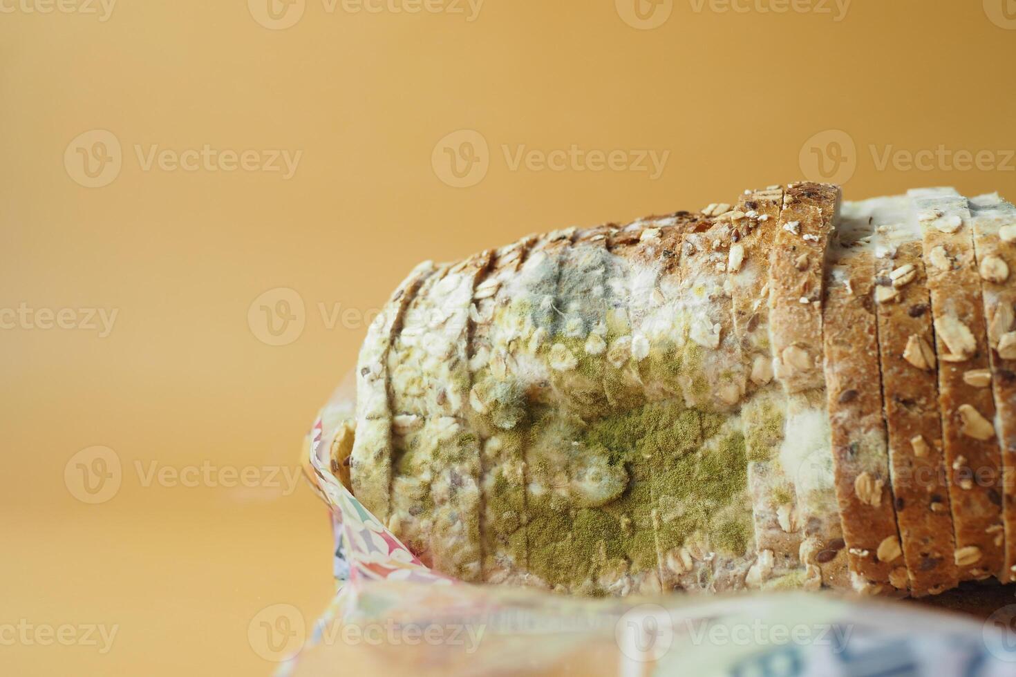 Close-Up of Mold-Infested Bread Slice on Orange Background photo