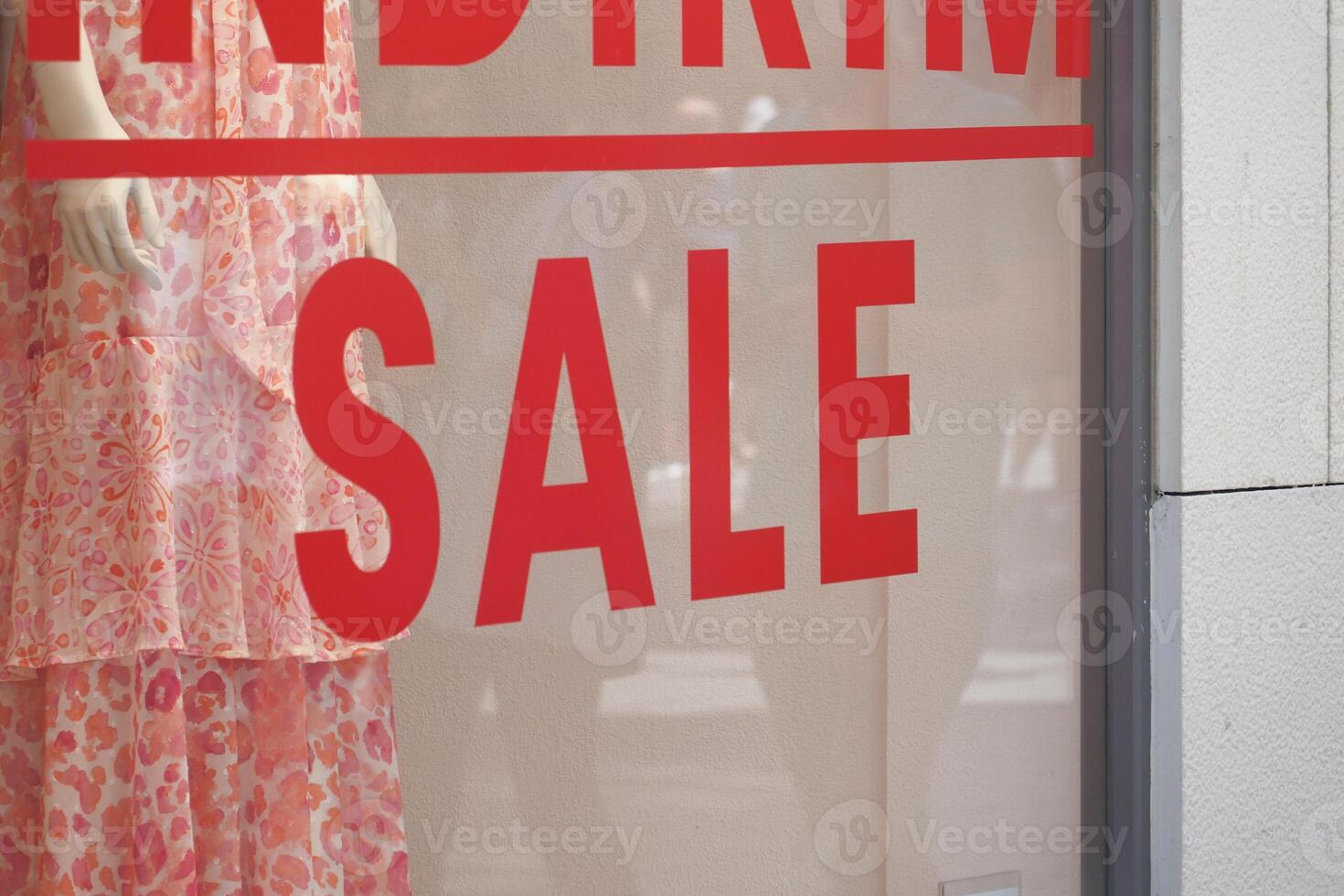 Large red Sale text letters on a glass wall obstruct a view inside the popular fashion store photo