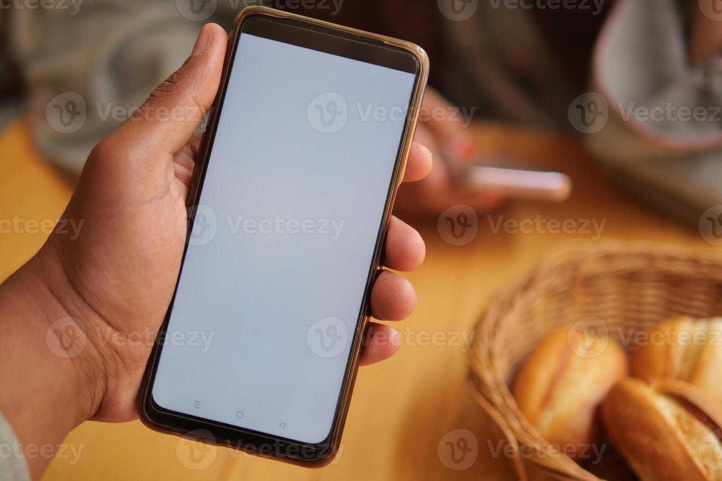 Person with a blank smartphone sitting at a cafe table during day photo