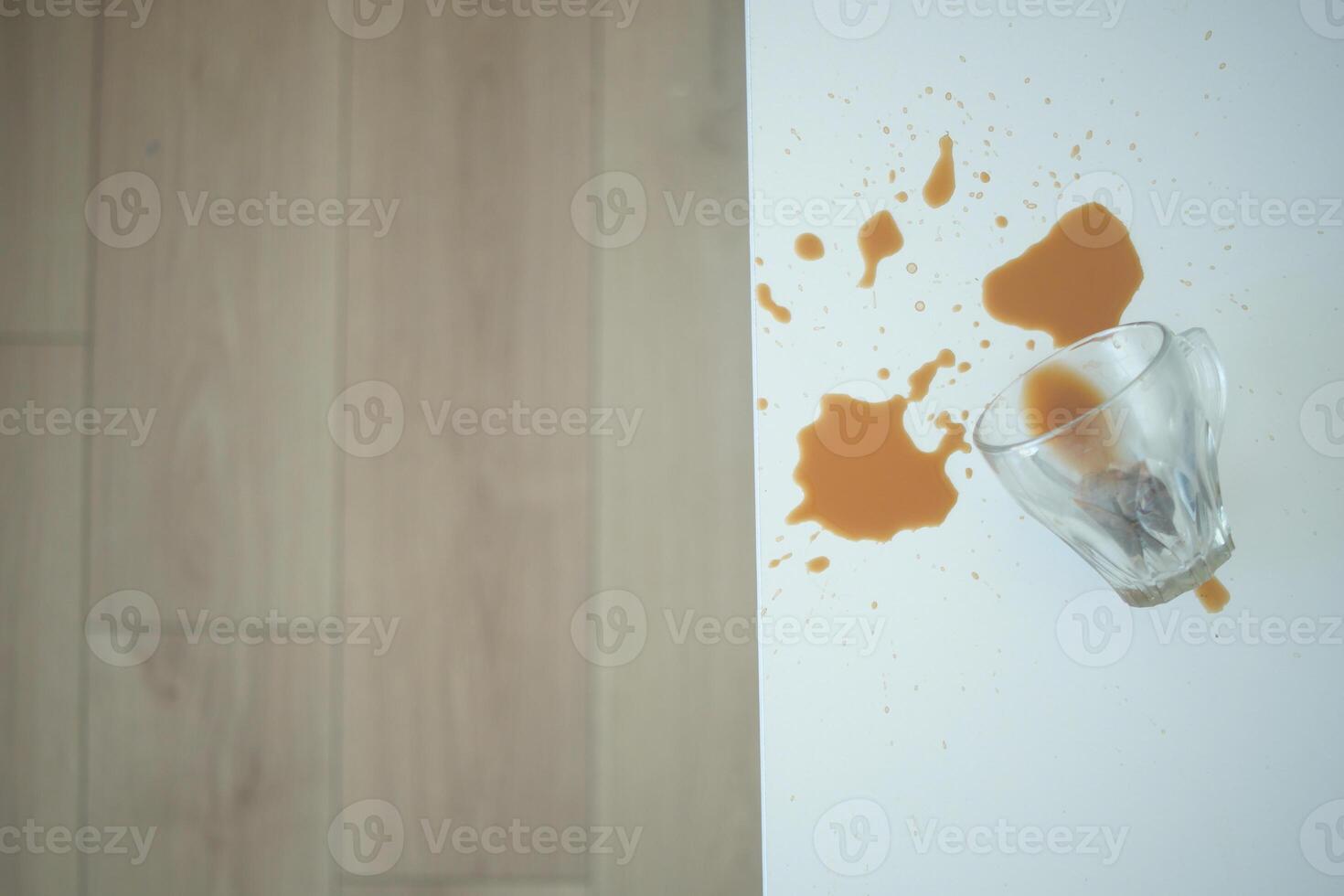 A drink was accidentally spilled on a desk with a laptop and glasses, creating a mess photo