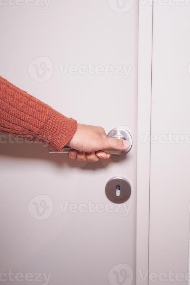 A Hand Reaching Out to Grasp the Door Knob in Order to Open a Door photo