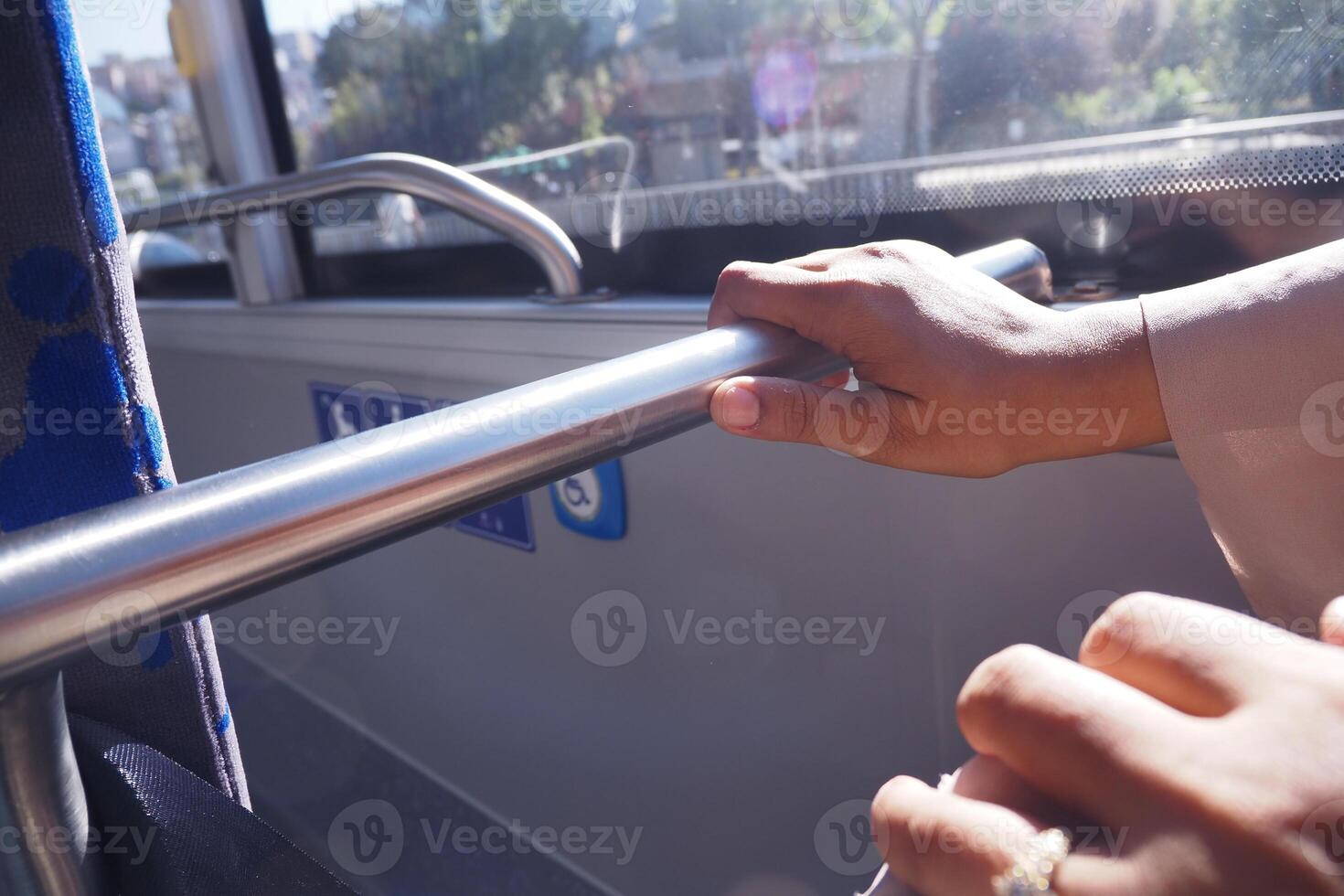 Close-up of Hands Holding Bus Rail in Sunny Public Transport photo
