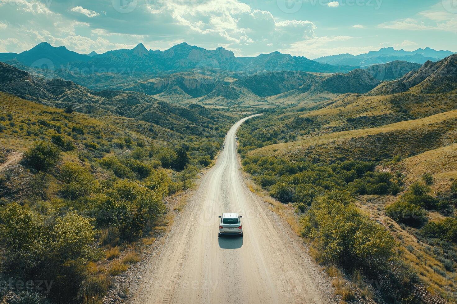 Car driving on a winding dirt road through desert mountains photo