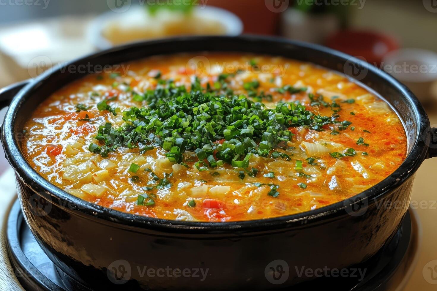 Hot moqueca capixaba fish stew simmering in a clay pot, garnished with chopped chives photo