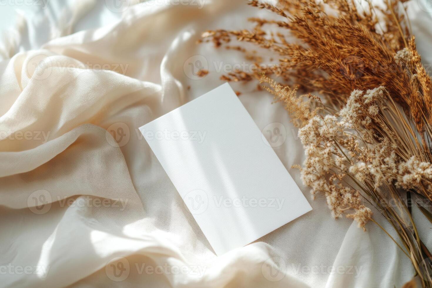 Blank card on soft fabric with dried flowers arranged on a light background in a serene setting photo