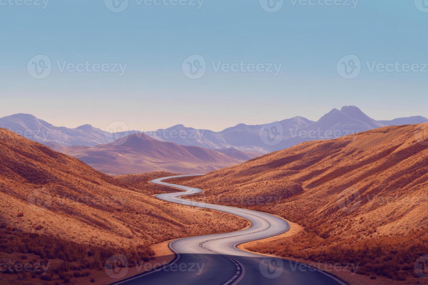 Winding road through arid landscape with mountains in the background at sunset photo