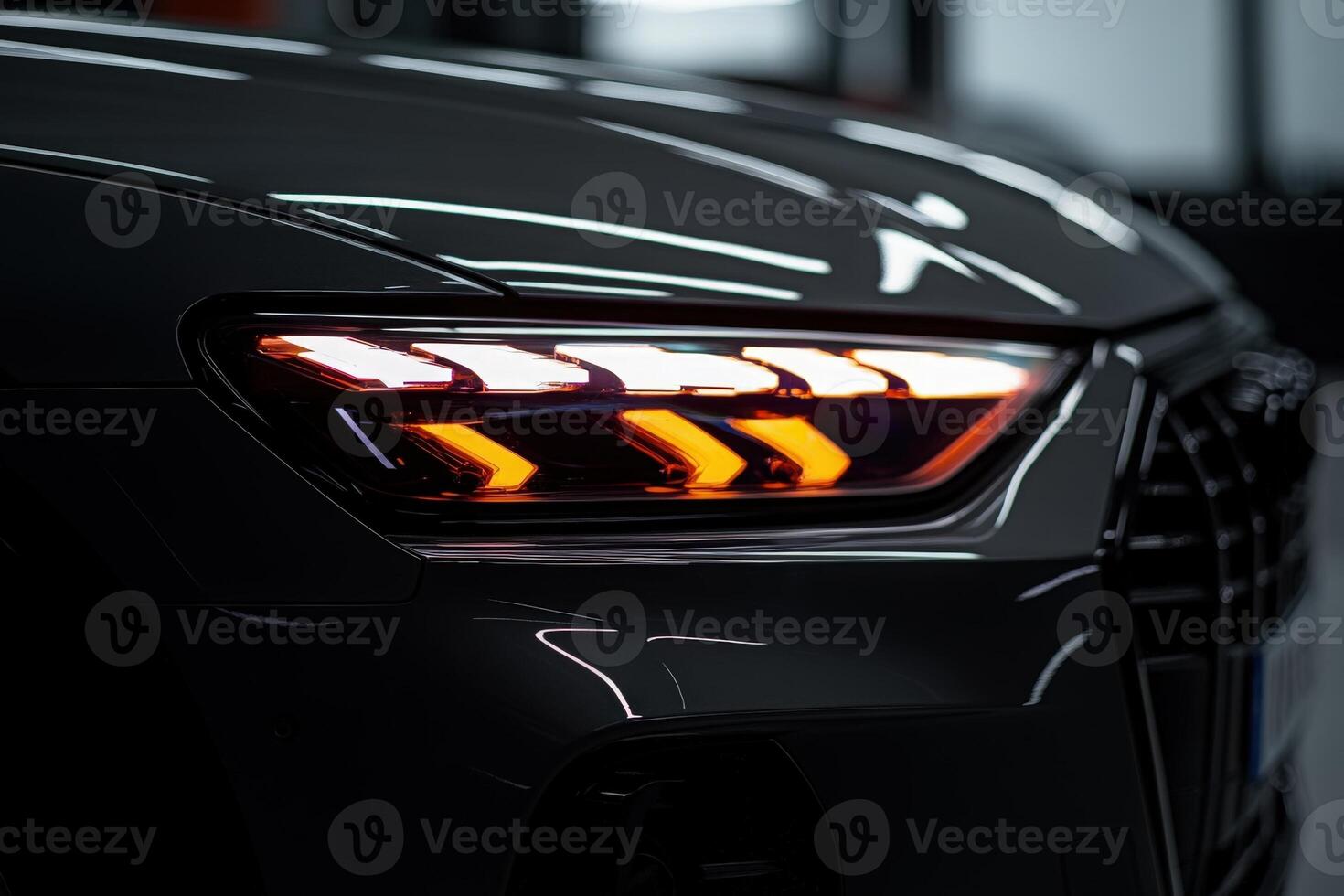 The close-up view of a stylish car headlight displays striking LED features glowing bright orange and white. The sleek contours highlight the modern design in a dimly lit showroom. photo