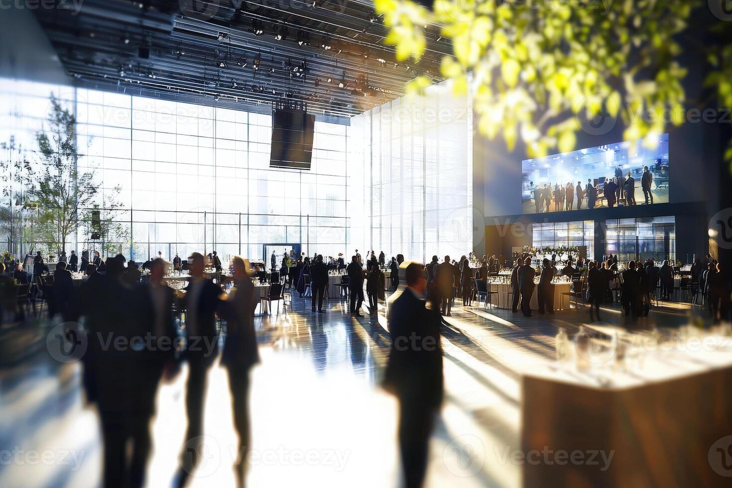 A busy conference hall filled with professionals networking and engaging in discussions. Large windows illuminate the space, creating a vibrant atmosphere for collaboration and interaction. photo