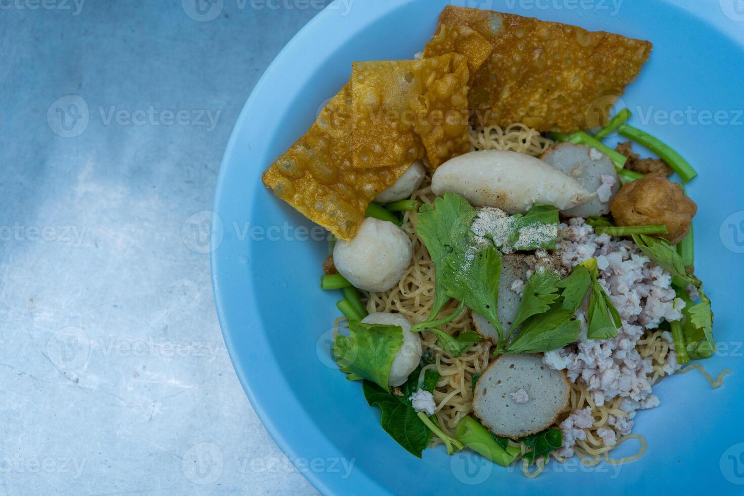 Egg noodles dried egg noodles with minced pork, fish meatballs, and fried dumplings. photo