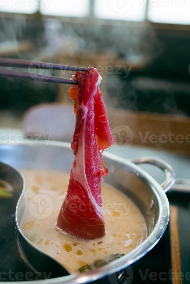 Man put to boiled soup in pot shabu by chopsticks with steam. photo