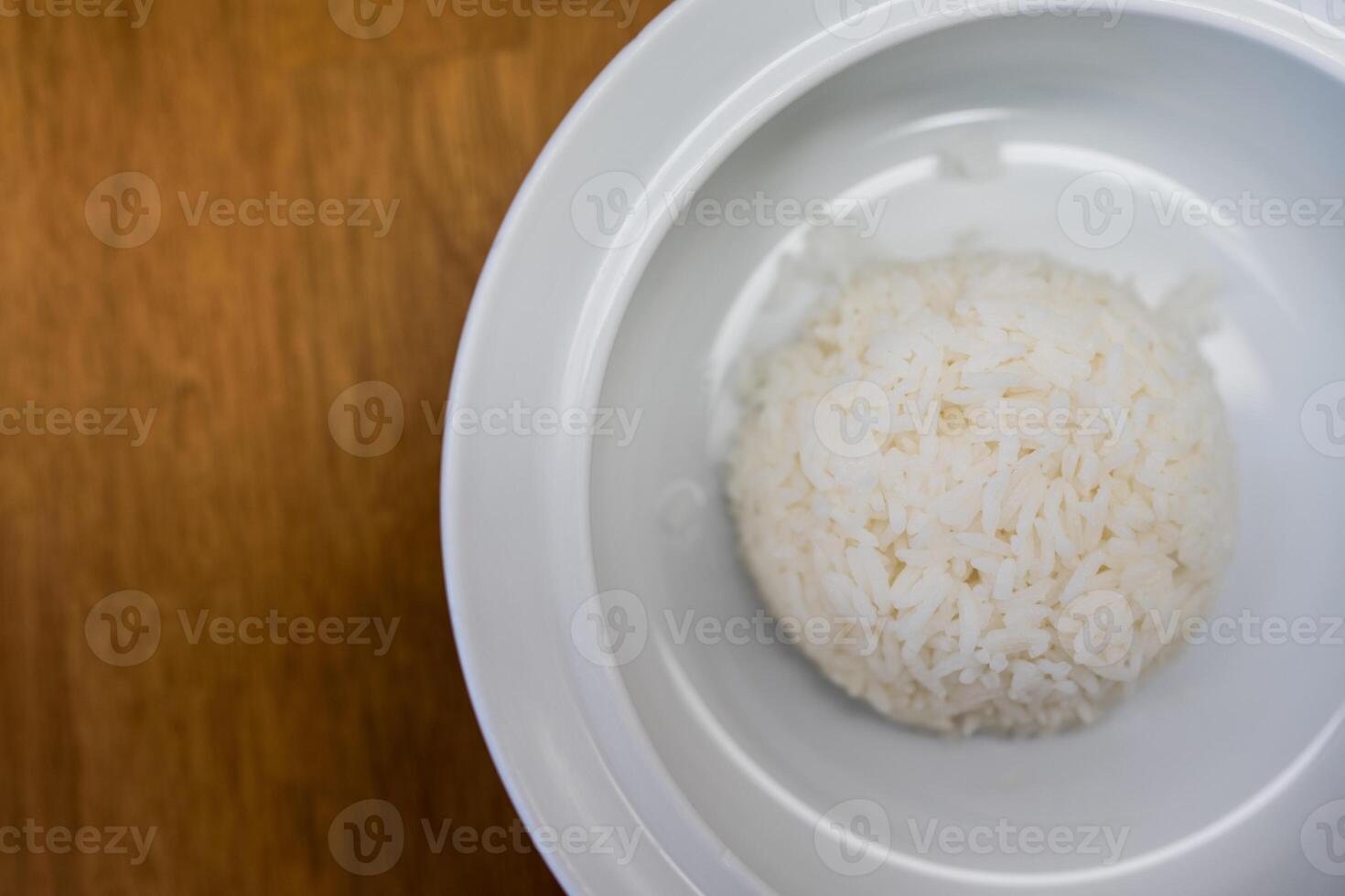 White bowl of tasty cooked white rice on wood table photo