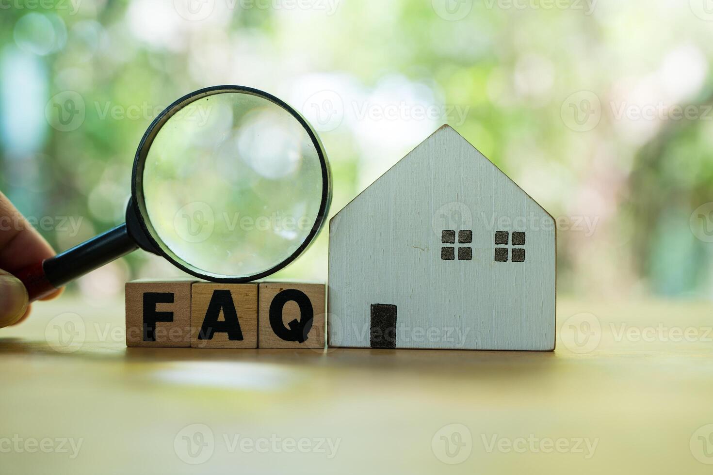 FAQ with wooden blocks alphabet letters and man holding a magnifying glass photo