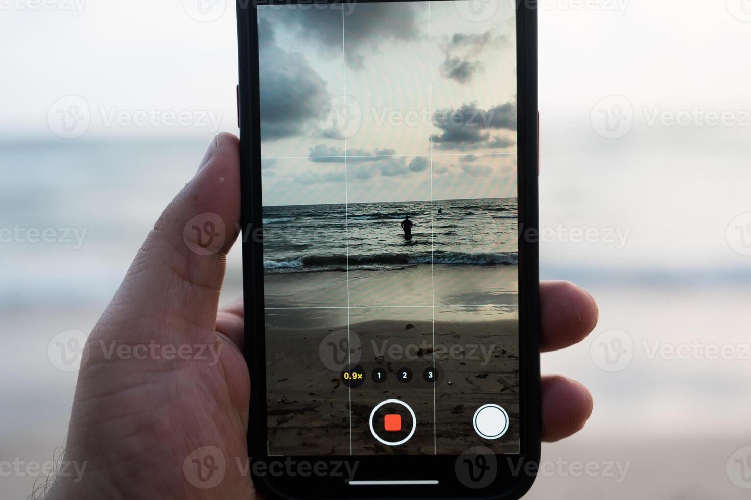 Shooting with phone. Shooting man walking at the beach photo