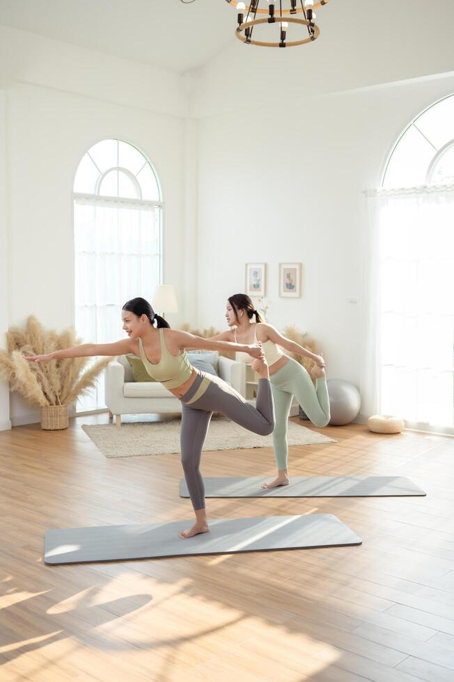 Two young Asian woman friends practicing yoga at home. photo