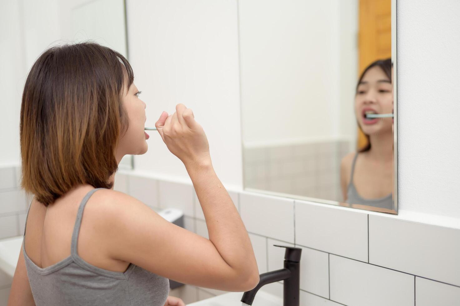 A young woman brushing her teeth in restroom photo