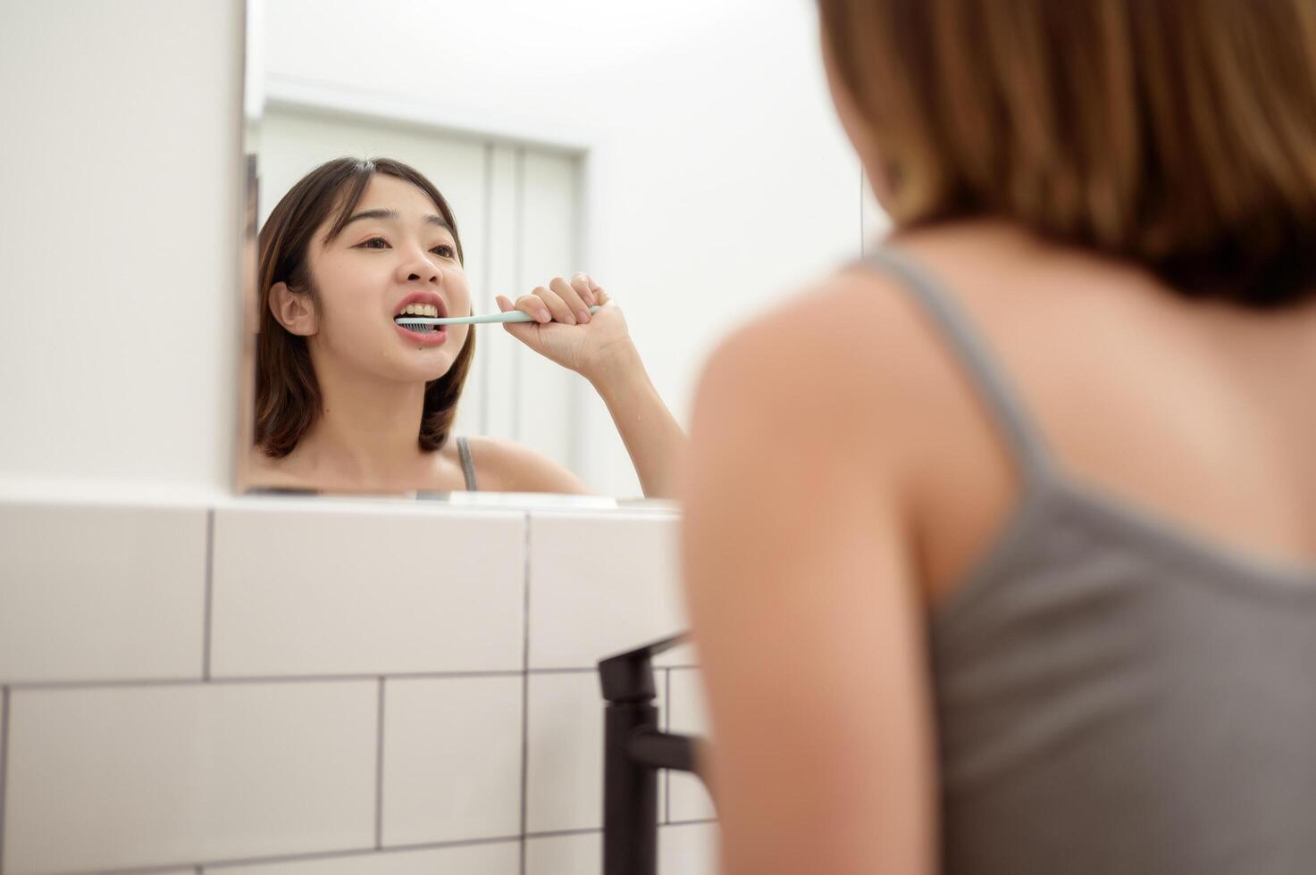A young woman brushing her teeth in restroom photo