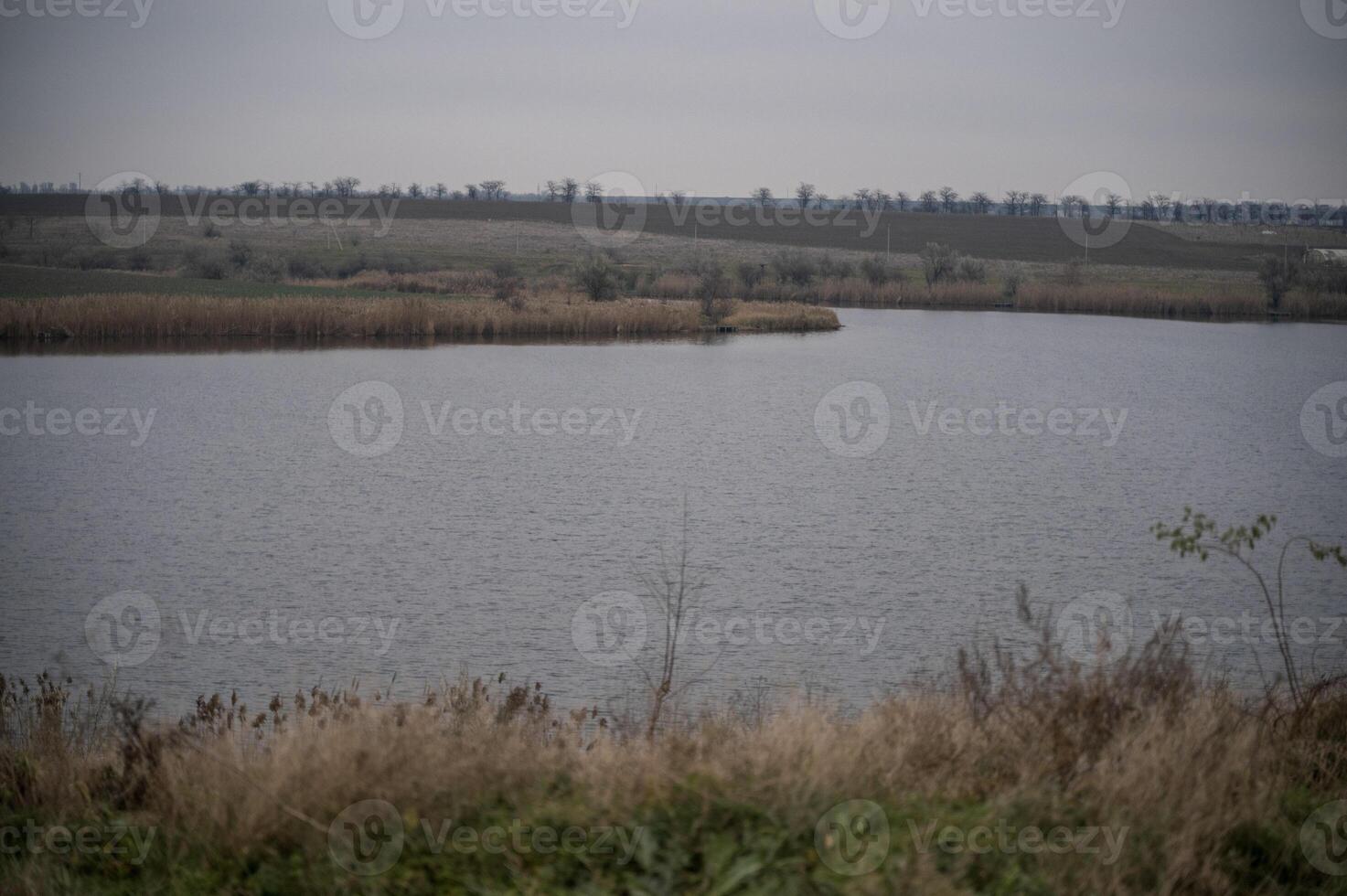 A man standing on a hill overlooking a lake photo
