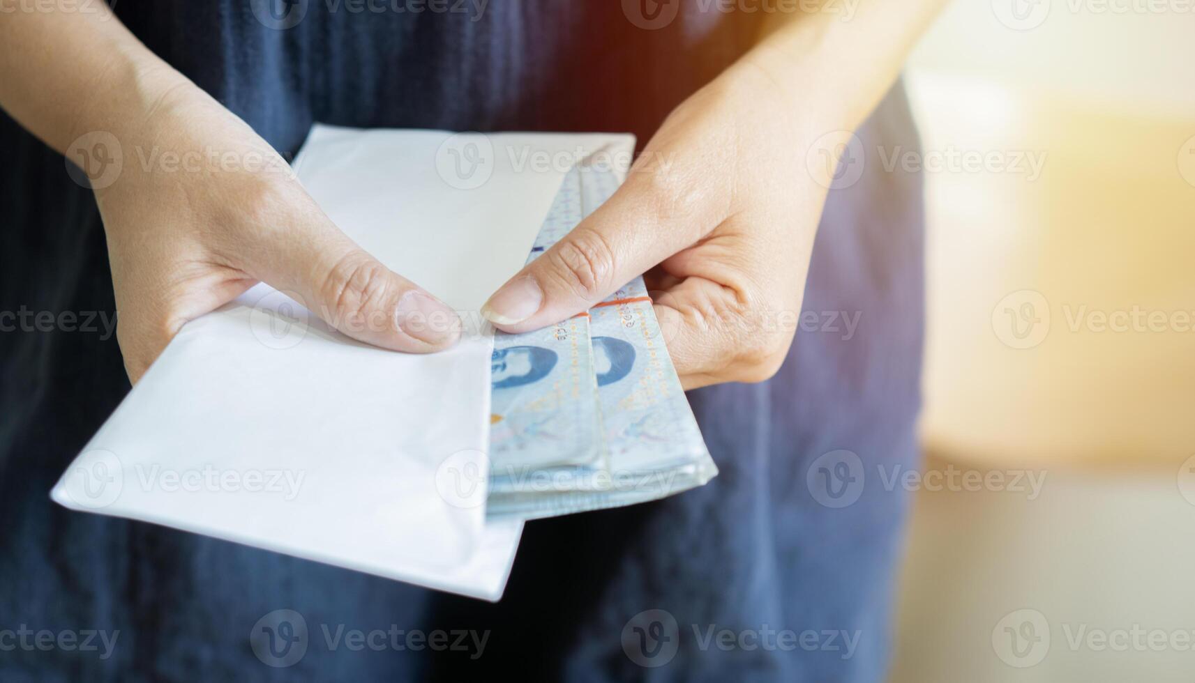 Hands holding envelope with Thai money and takes out money from an envelope, close-up. photo