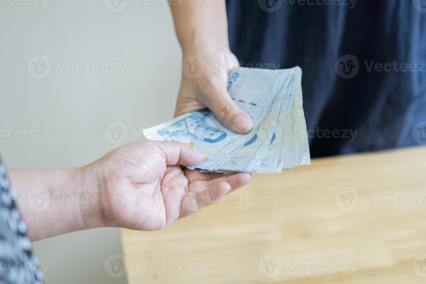 Close up of two hands taking and giving Thai bank notes. Hand receiving money, note to buy and sell. photo