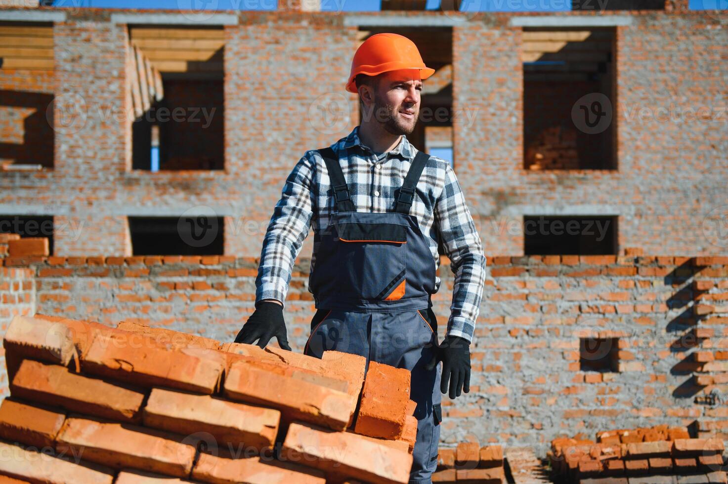Young adult man builder working at object carrying bricks at construction site photo