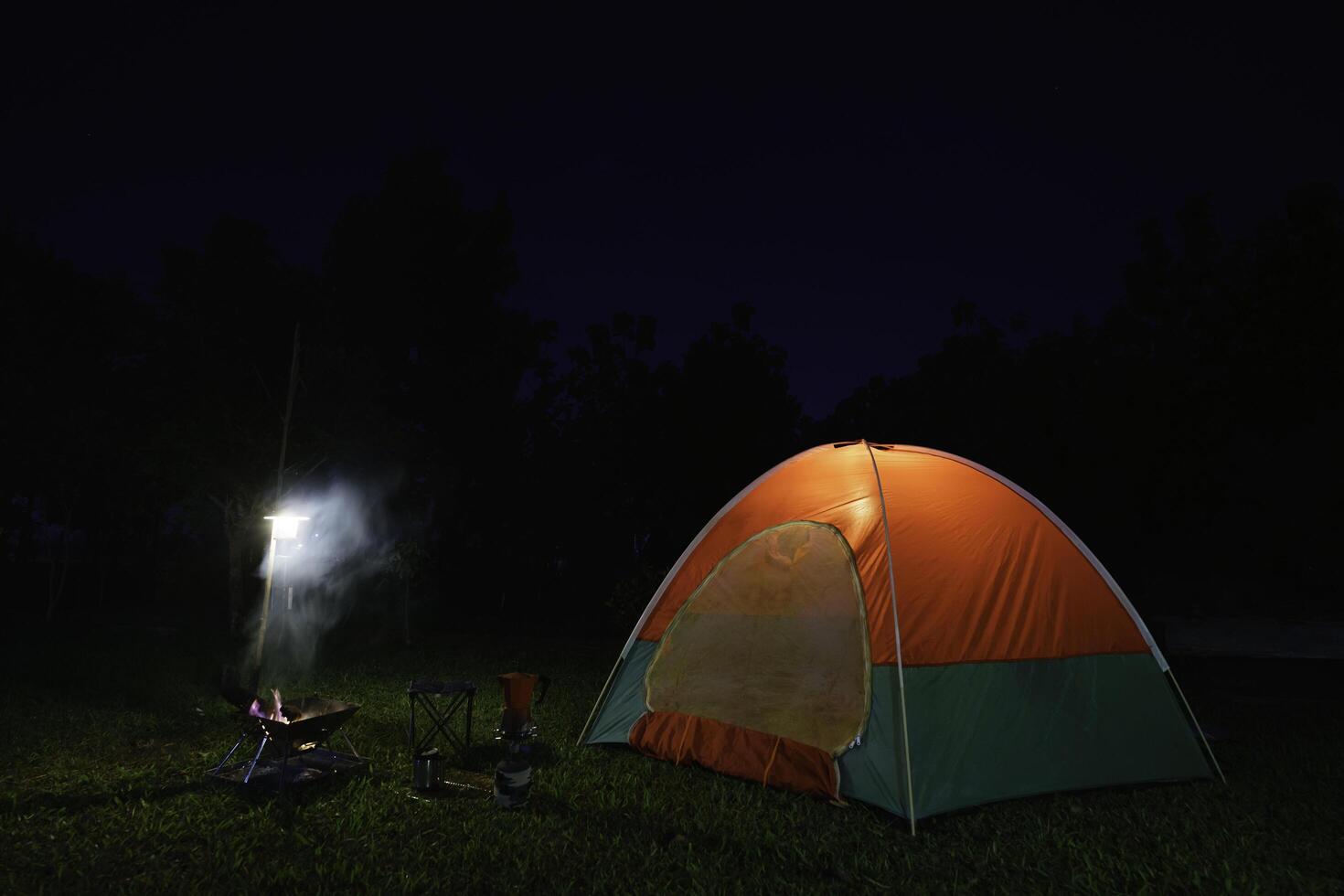 camping tent in the forest with green trees, camping in the forest at night, Small gas lantern photo
