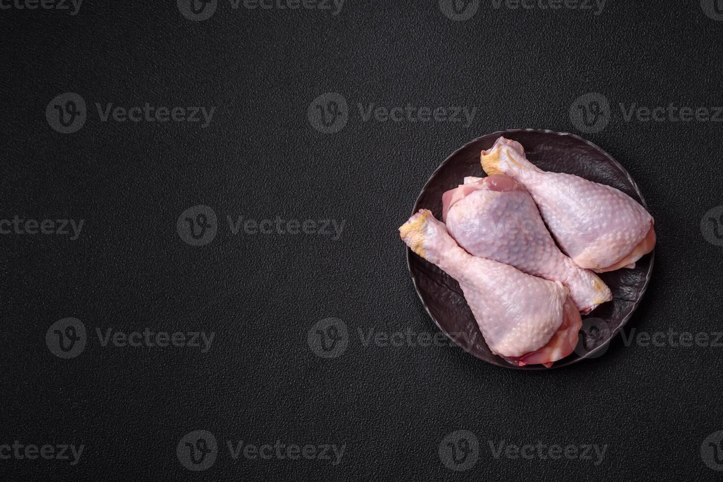 Raw chicken or turkey legs with salt, spices and herbs photo