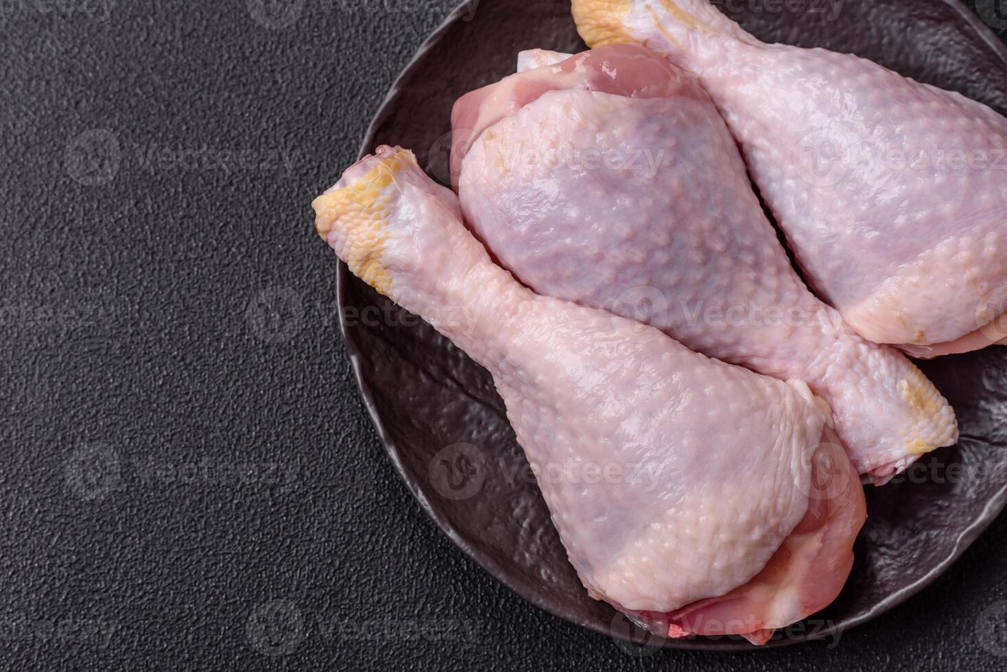 Raw chicken or turkey legs with salt, spices and herbs photo