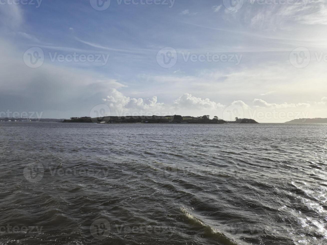 Spike Island in Ireland as it is seen from another island, with ocean waters and cloudy sky photo