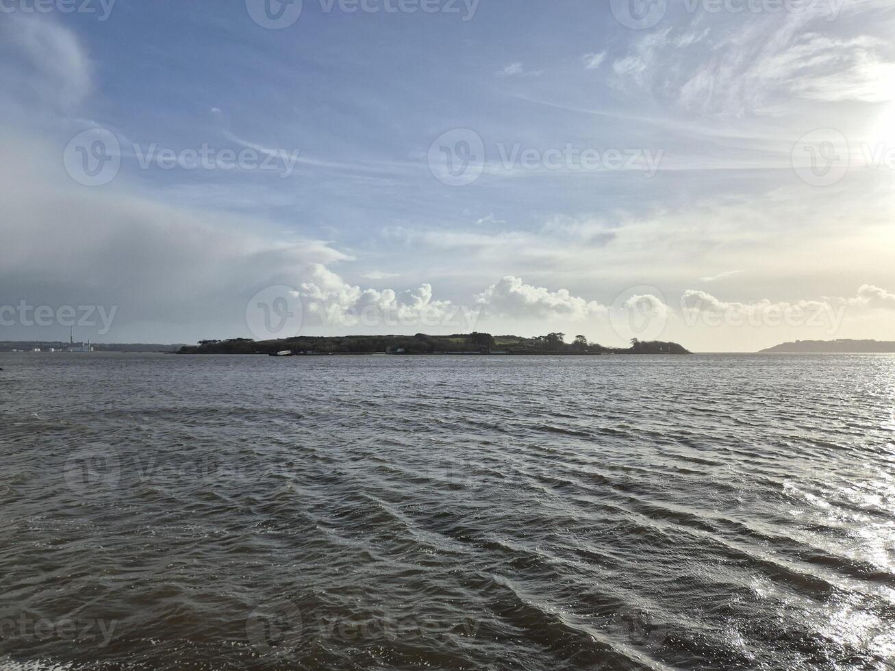 Spike Island in Ireland as it is seen from another island, with ocean waters and cloudy sky photo
